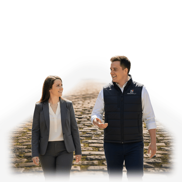 The director of Cobble Road Labs, and a female client walk and talk on a cobblestone path. Both are smiling, suggesting a positive, collaborative atmosphere. The background is a soft gradient.